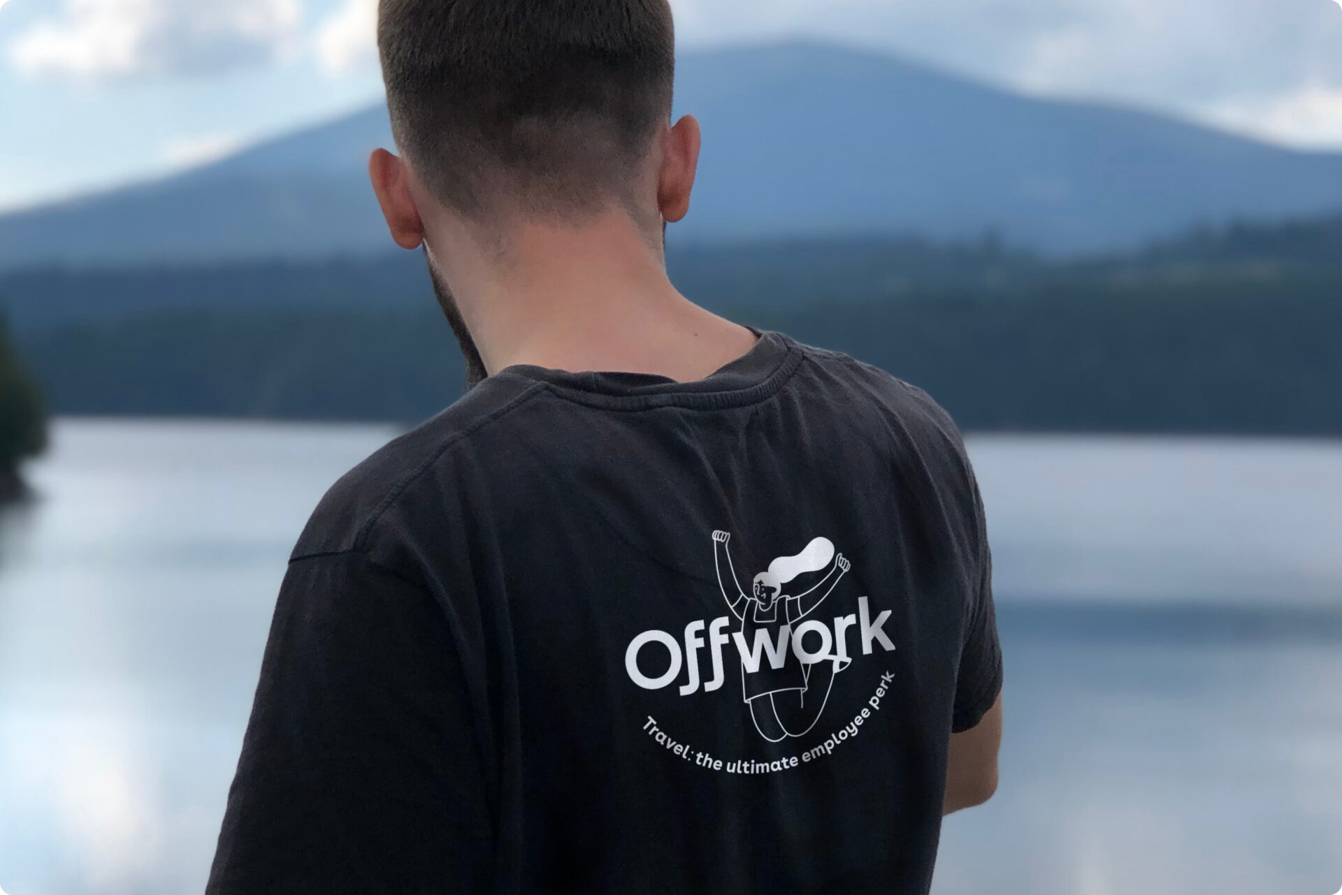 A man standing in front of a body of water wearing Offwork tshirt